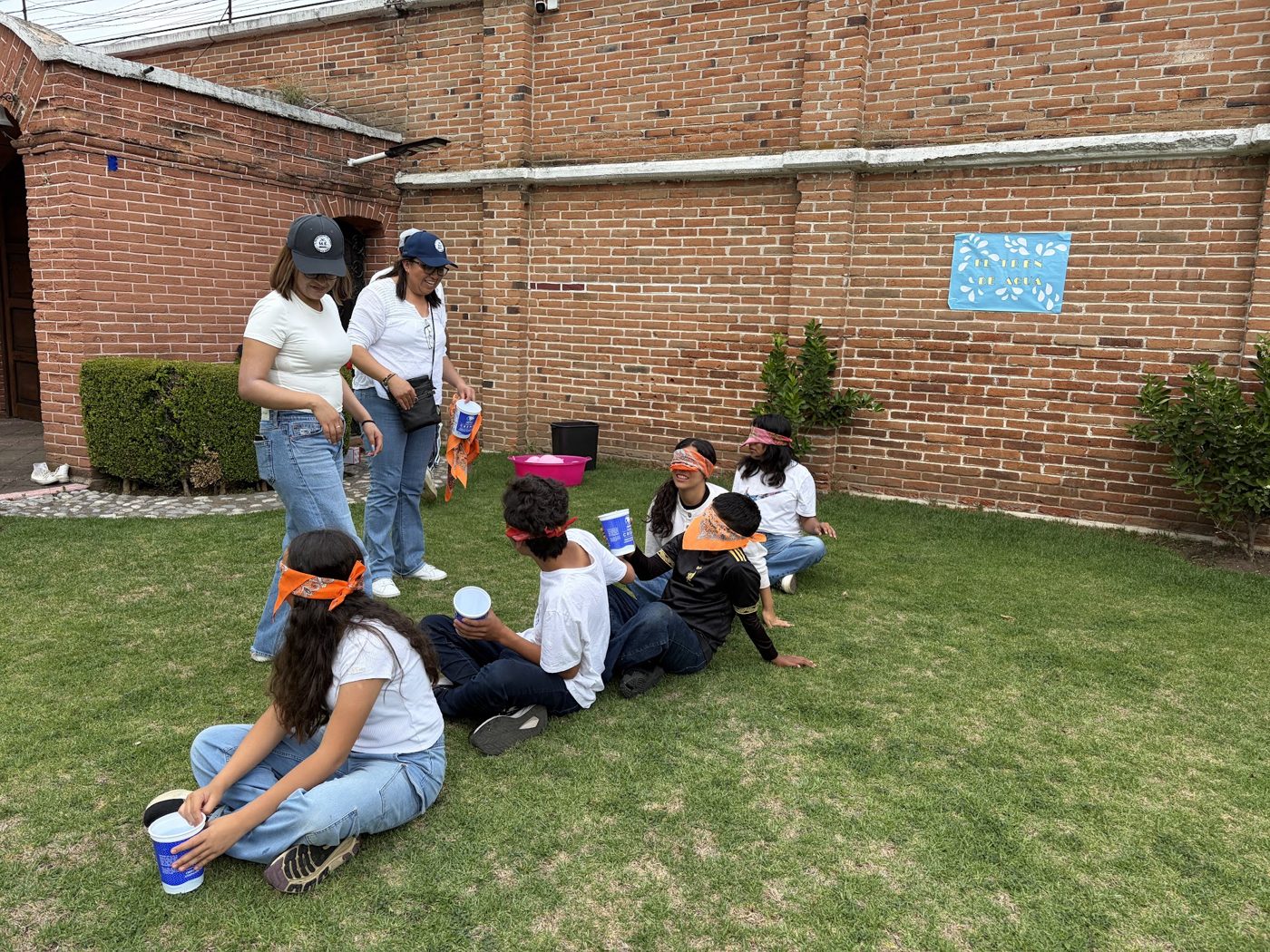Maestra leyendo con un grupo pequeño de alumnos bajo un árbol